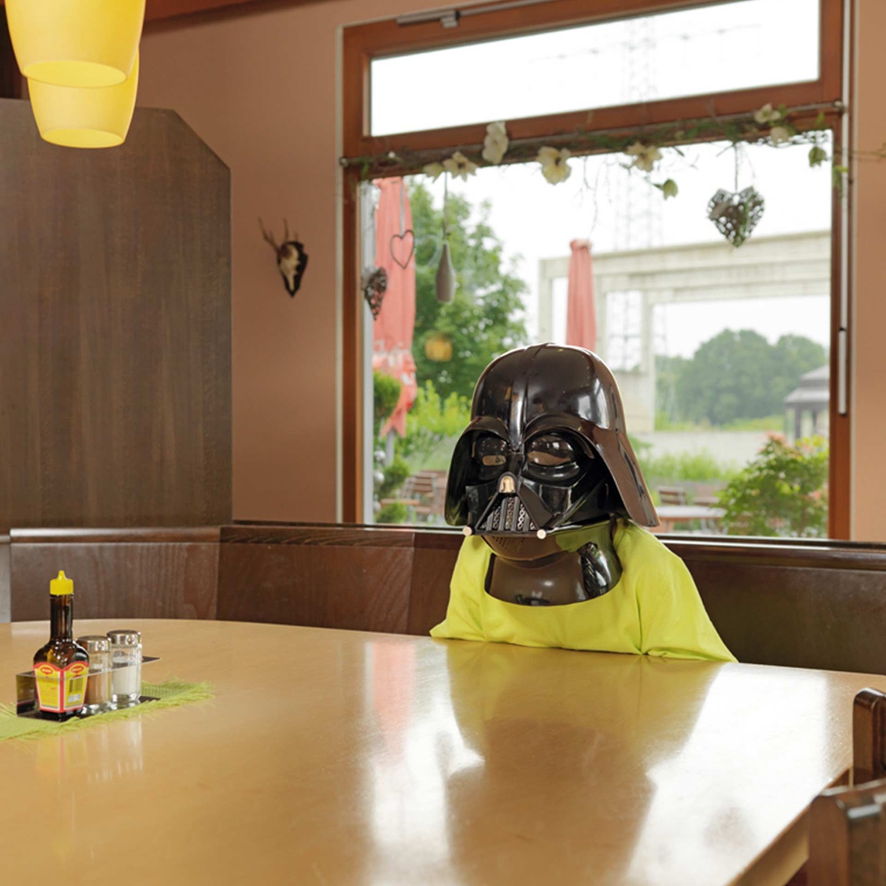 Kleiner Junge mit Darth Vader Maske sitzt an einem Restauranttisch und wartet