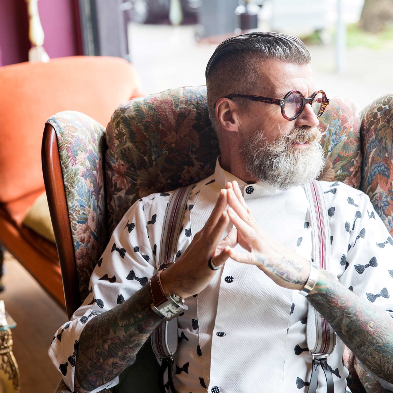 Modischer Mann mit Bart Brille und Hemd sitzt in einem Designerstuhl