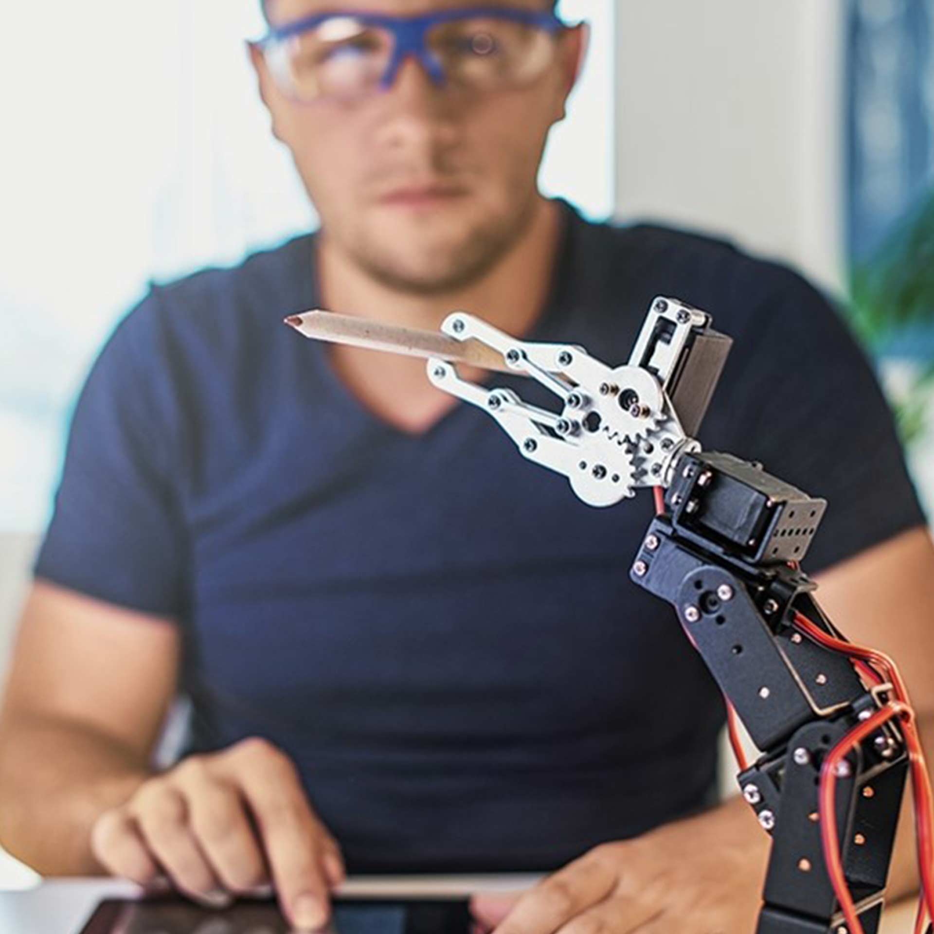 Mann mit Tablet steuert einen Roboter der einen Buntstift hält