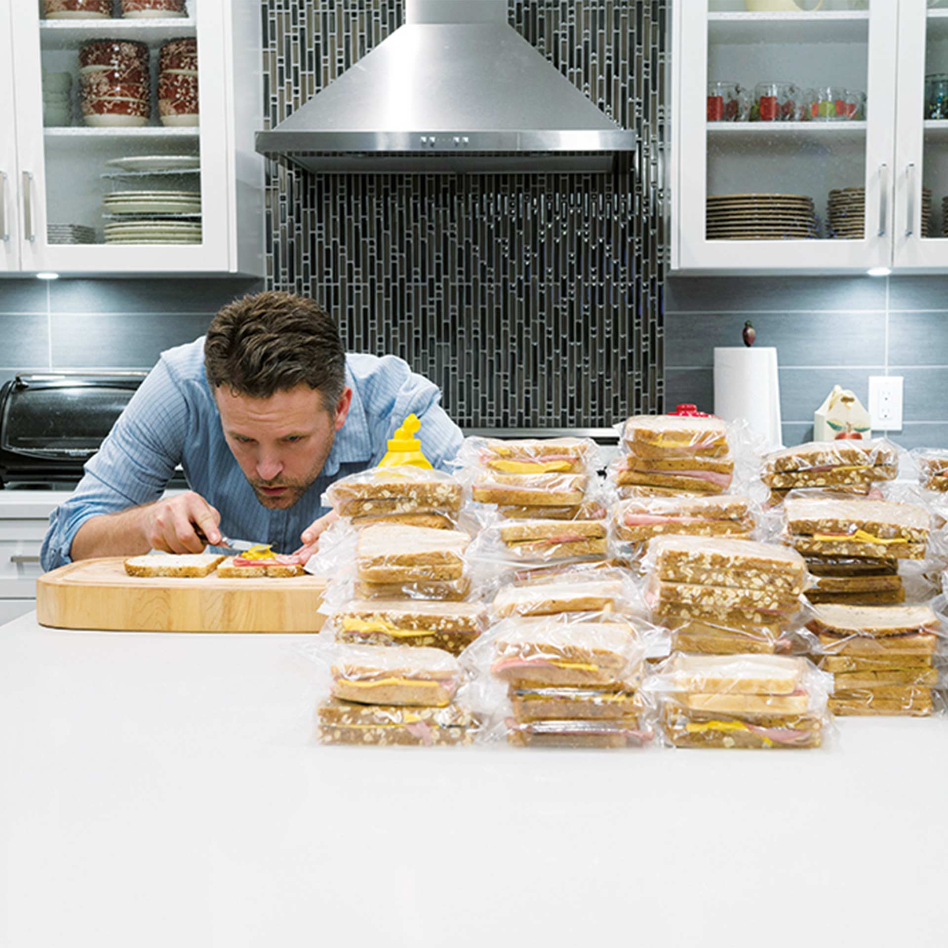Ein junger Mann bereitet mehrer Sandwiches vor