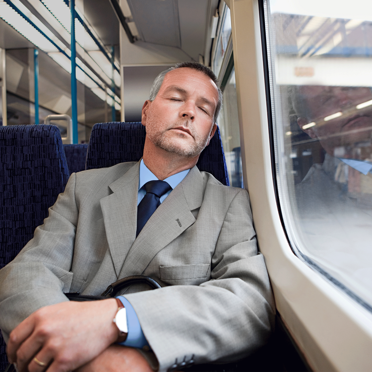 Mann im Anzug sitzend im Zug und am schlafen