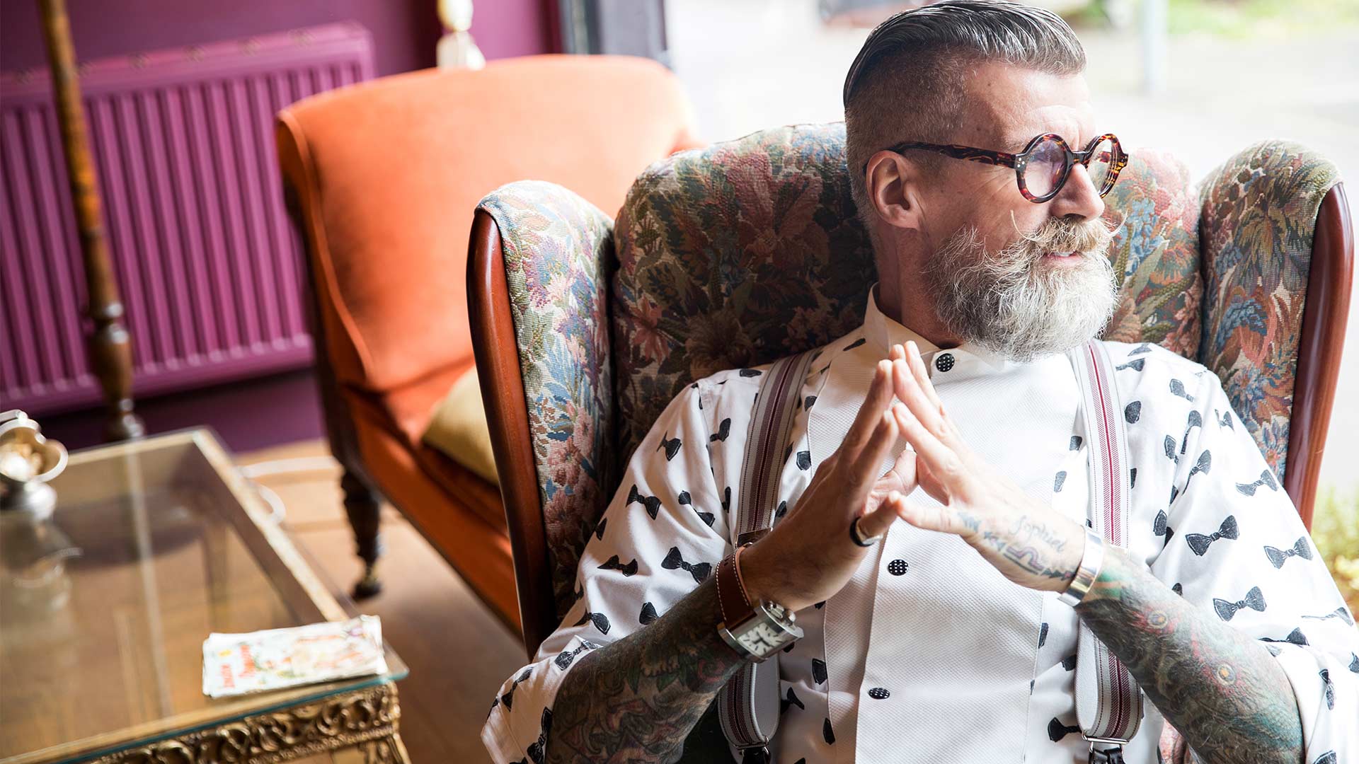 Modischer Mann mit Bart Brille und Hemd sitzt in einem Designerstuhl