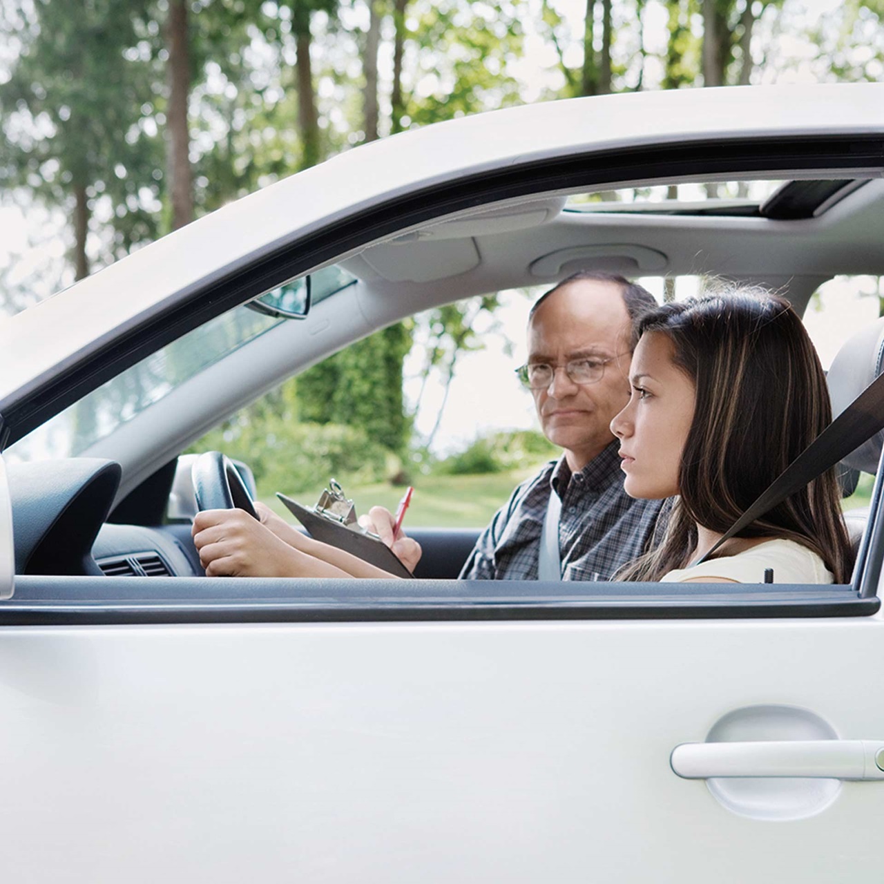 Junge Frau bei der Autoprüfung und der Experte schaut grimmig zu ihr rüber