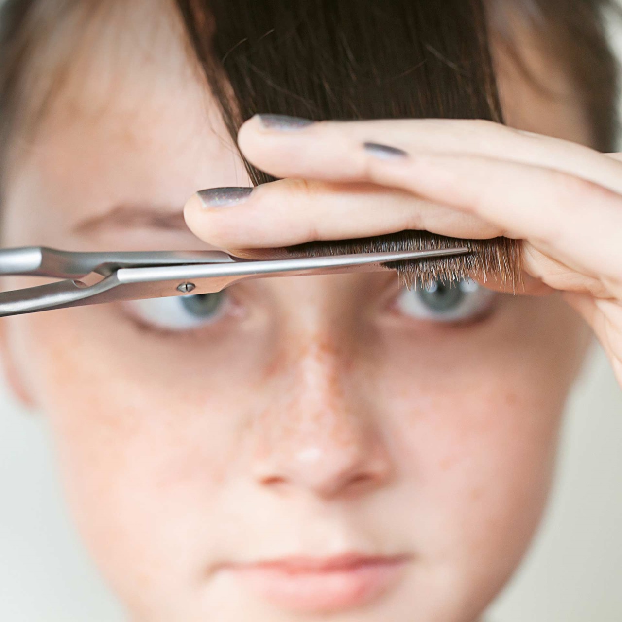 Teenager-Mädchen schneidet sich ihre Fransen mit einer Schere