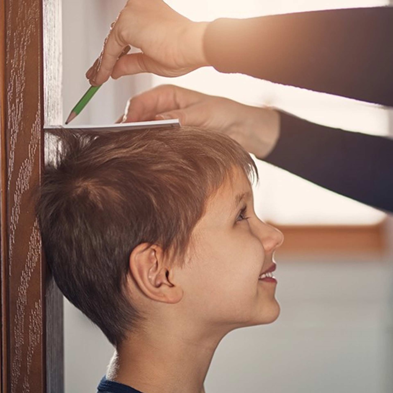 Kleiner Junge wird an einem Türpfosten von seiner Mutter in der Grösse gemessen