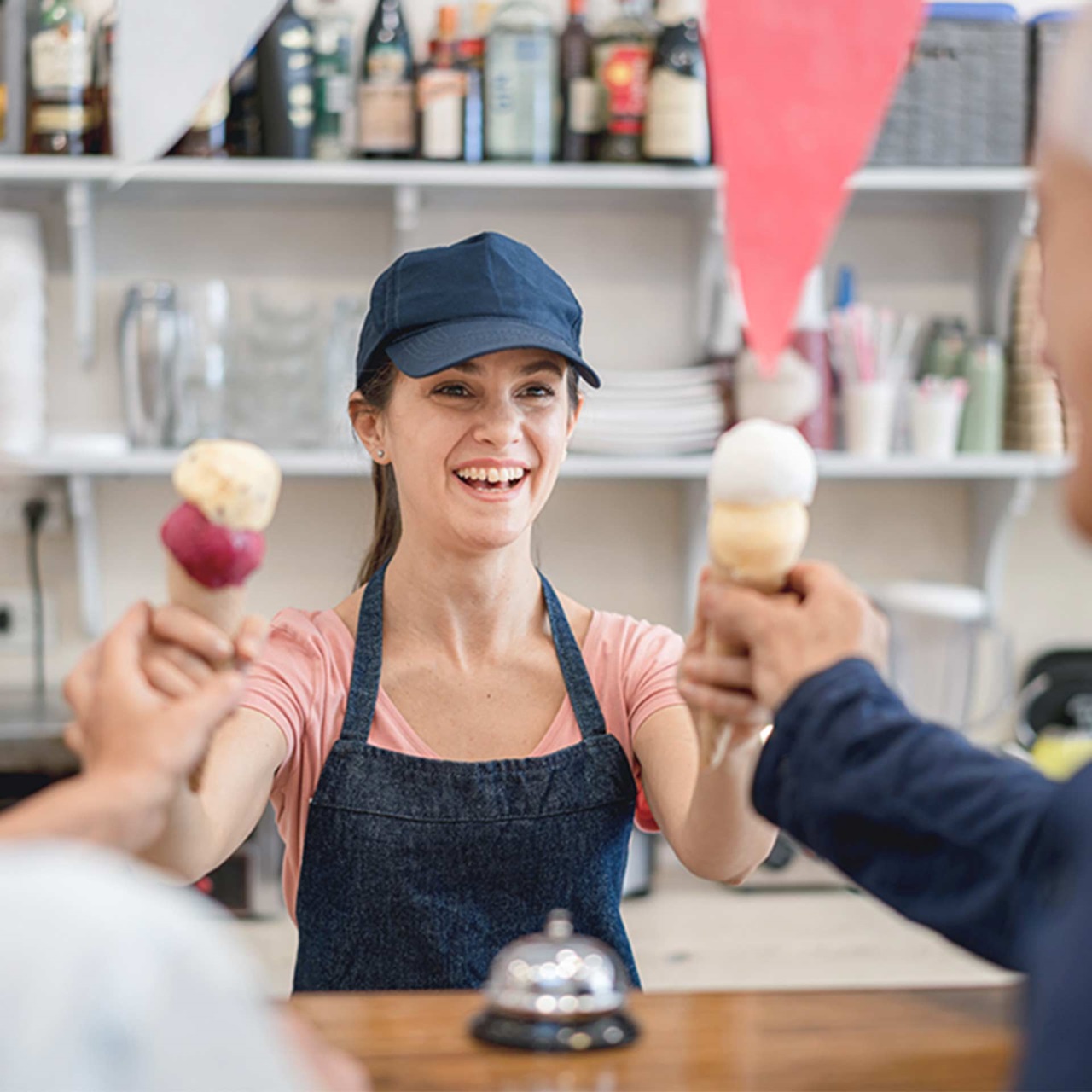 Eisverkäuferin lächelt und streckt zwei Cornet Glace an ein älteres Pärchen aus