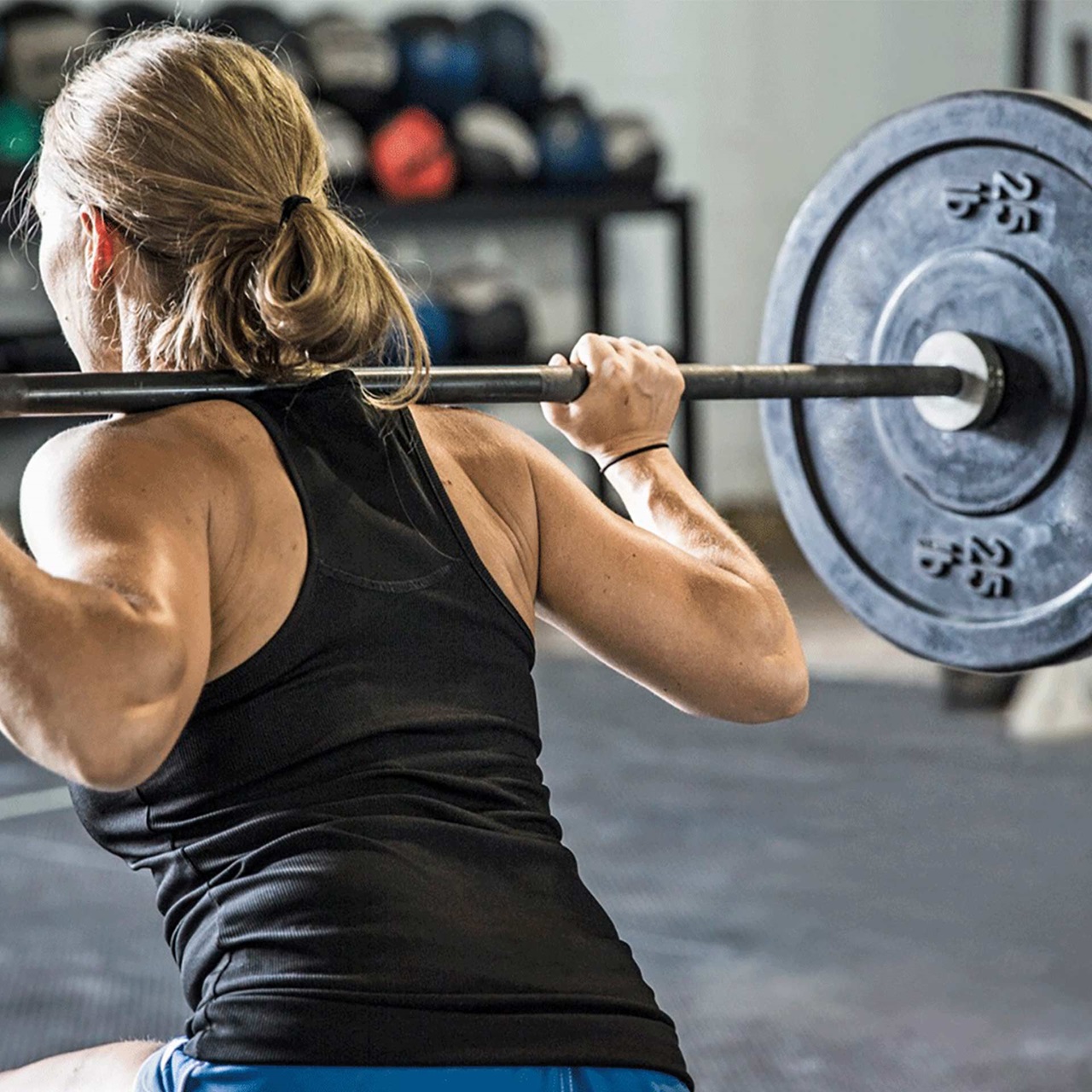Frau stemmt Gewichte auf den Schultern