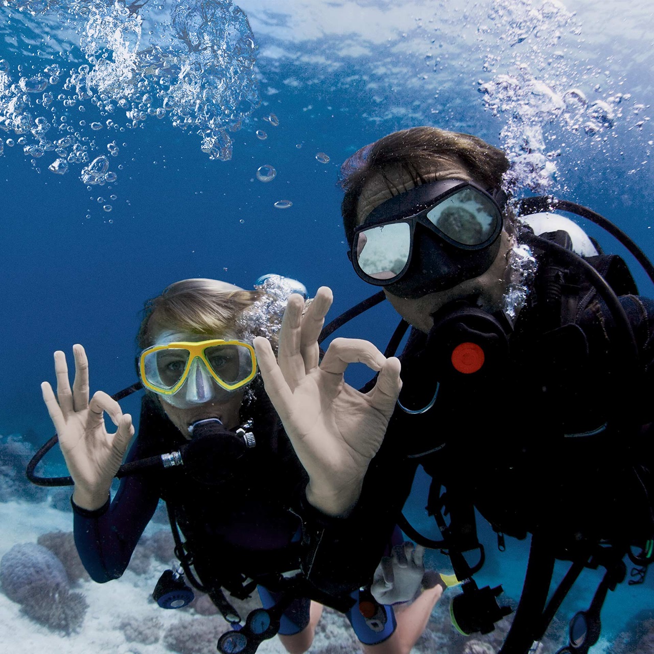 Zwei Taucher schauen zur Kamera und geben das Ok-Zeichen