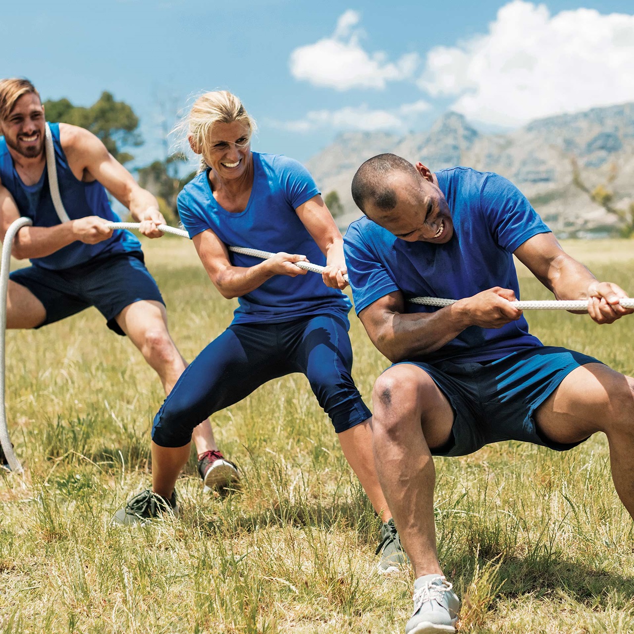 Drei Männer in Sportkleidung ziehen an einem Seil