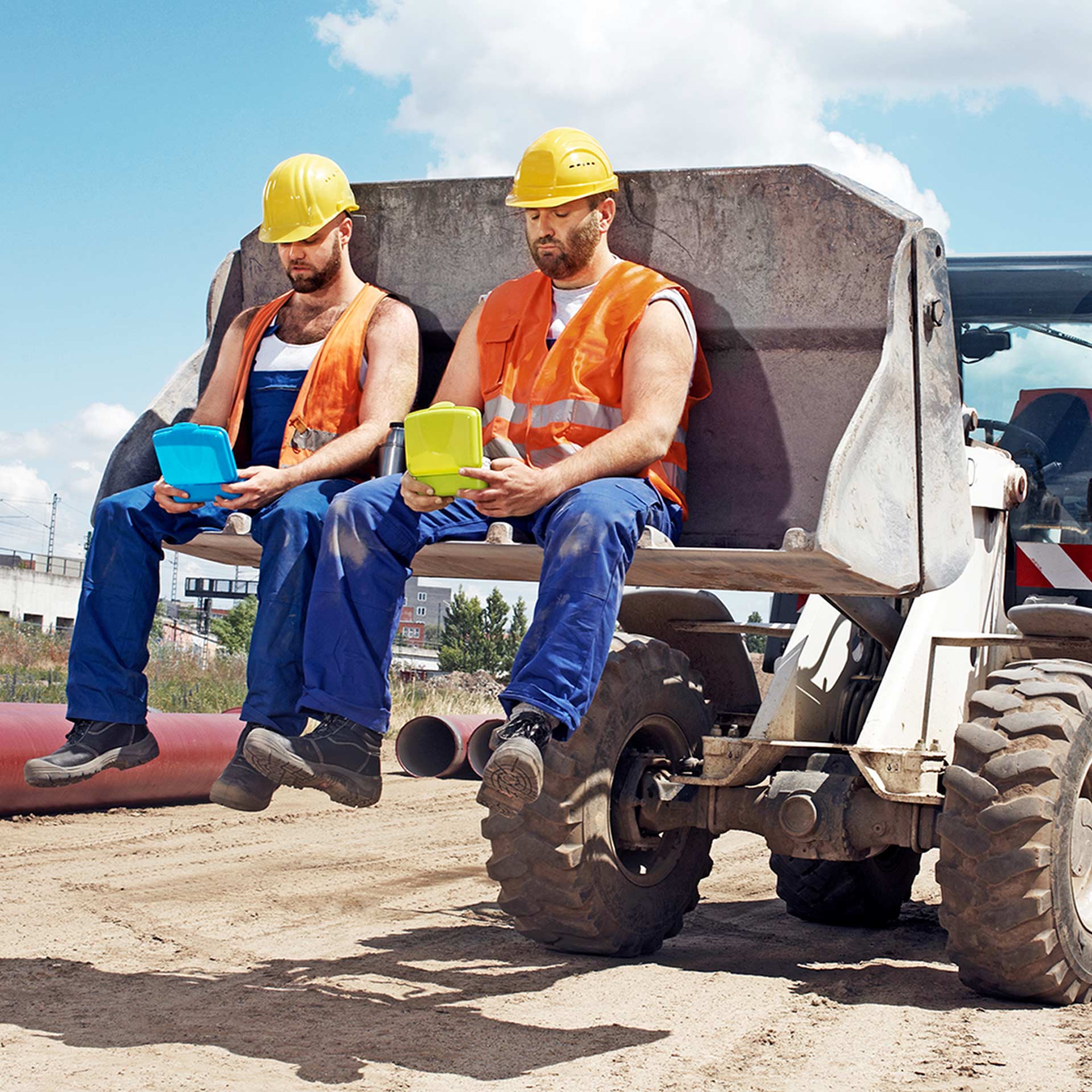 Zwei Bauarbeiter sitzend auf einer Baggerschaufel und starren ihre Lunchboxen an